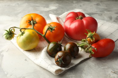 Photo of Different ripe tomatoes on grey textured table