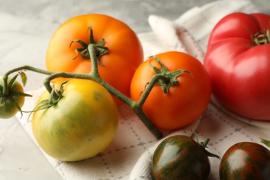 Photo of Different ripe tomatoes on grey textured table, closeup