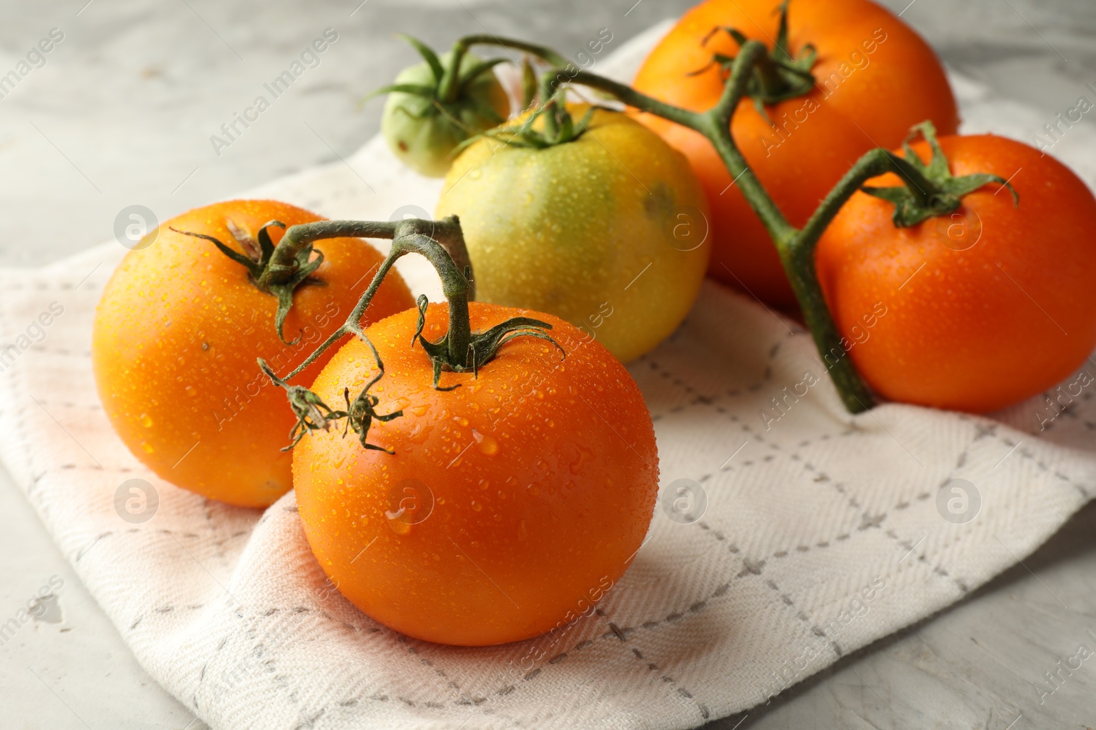 Photo of Branch of yellow tomatoes on grey textured table, closeup