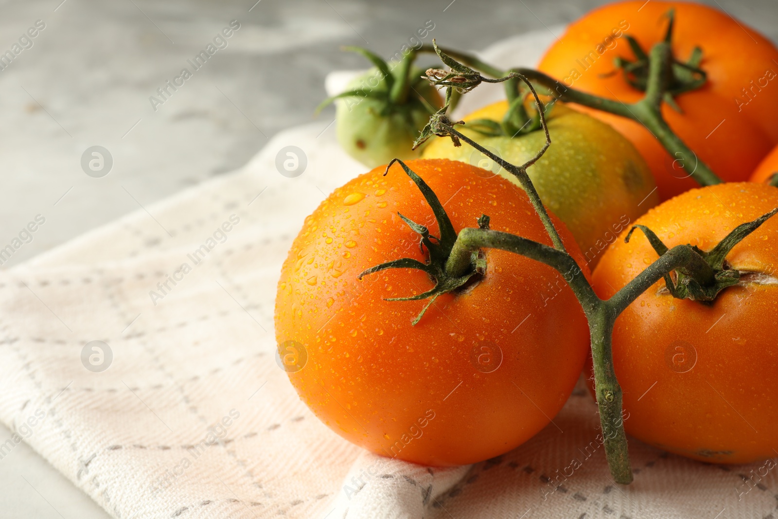 Photo of Branch of yellow tomatoes on grey textured table, closeup