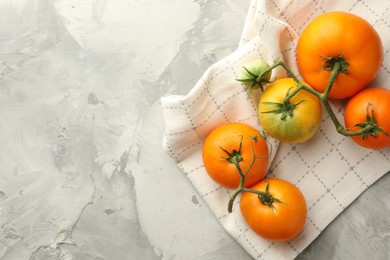 Branch of yellow tomatoes on grey textured table, top view. Space for text