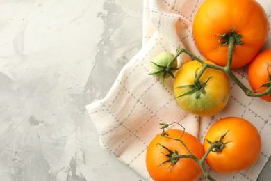 Branch of yellow tomatoes on grey textured table, top view. Space for text