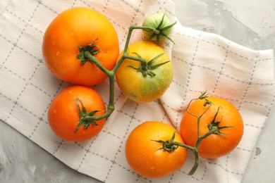 Photo of Branch of yellow tomatoes on grey textured table, top view