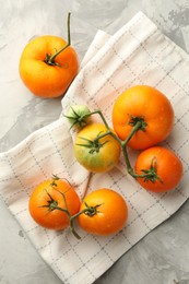 Branch of yellow tomatoes on grey textured table, top view