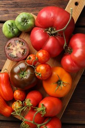 Different ripe tomatoes on wooden table, top view