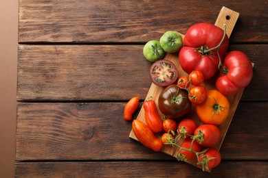 Different ripe tomatoes on wooden table, top view. Space for text