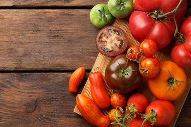 Different ripe tomatoes on wooden table, top view. Space for text