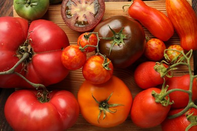 Different ripe tomatoes on wooden table, top view