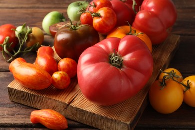 Different ripe tomatoes on wooden table, closeup