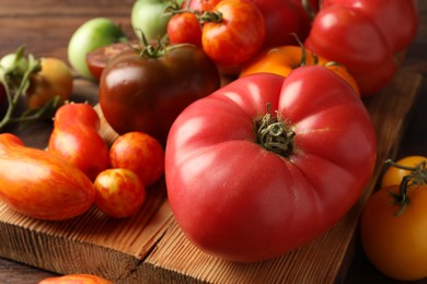 Different ripe tomatoes on wooden table, closeup