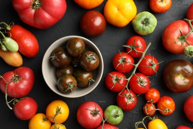 Photo of Different fresh tomatoes on grey textured table, flat lay