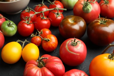 Photo of Many different fresh tomatoes on grey table, closeup