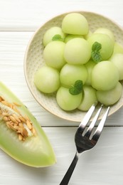 Photo of Melon balls in bowl and fresh fruit on wooden table, top view