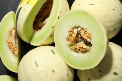 Photo of Fresh ripe honeydew melons on dark table, top view