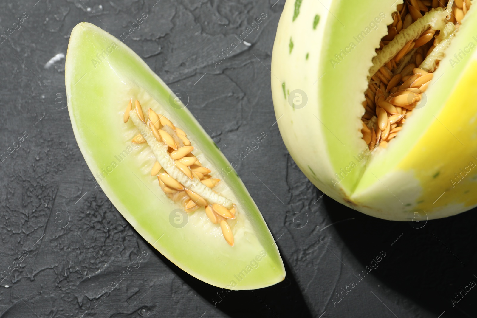 Photo of Fresh ripe honeydew melon on dark table, top view