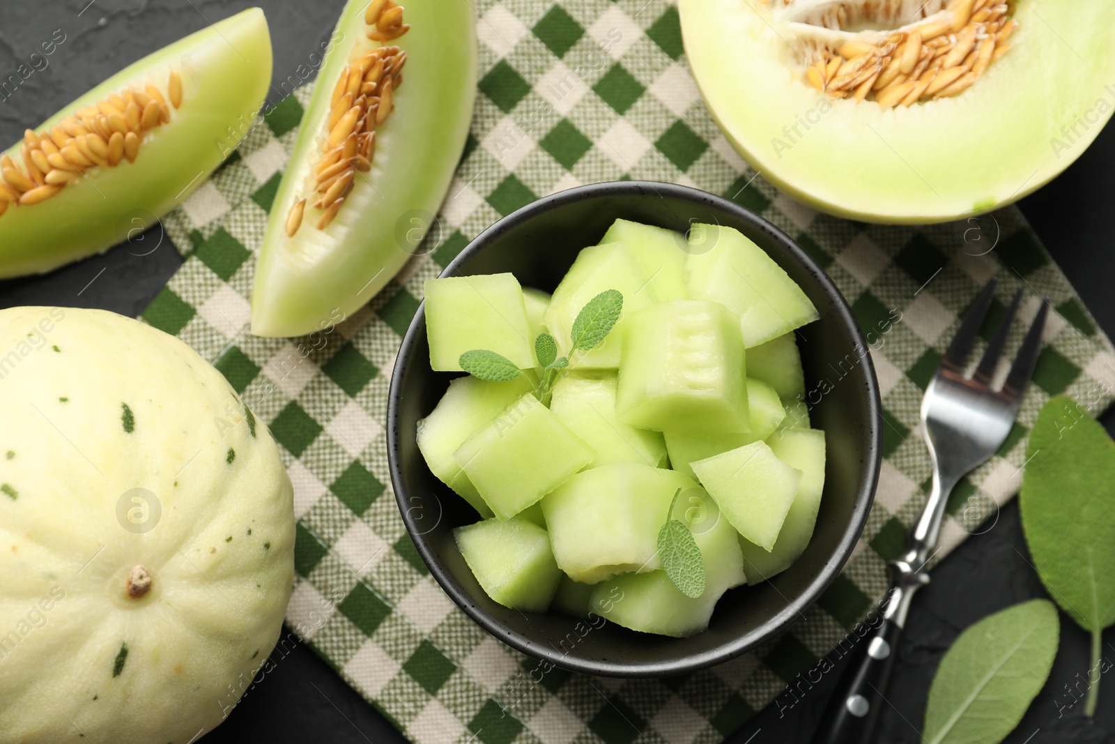 Photo of Slices of yummy melon on dark table, flat lay