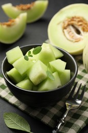 Photo of Slices of yummy melon on dark table, closeup