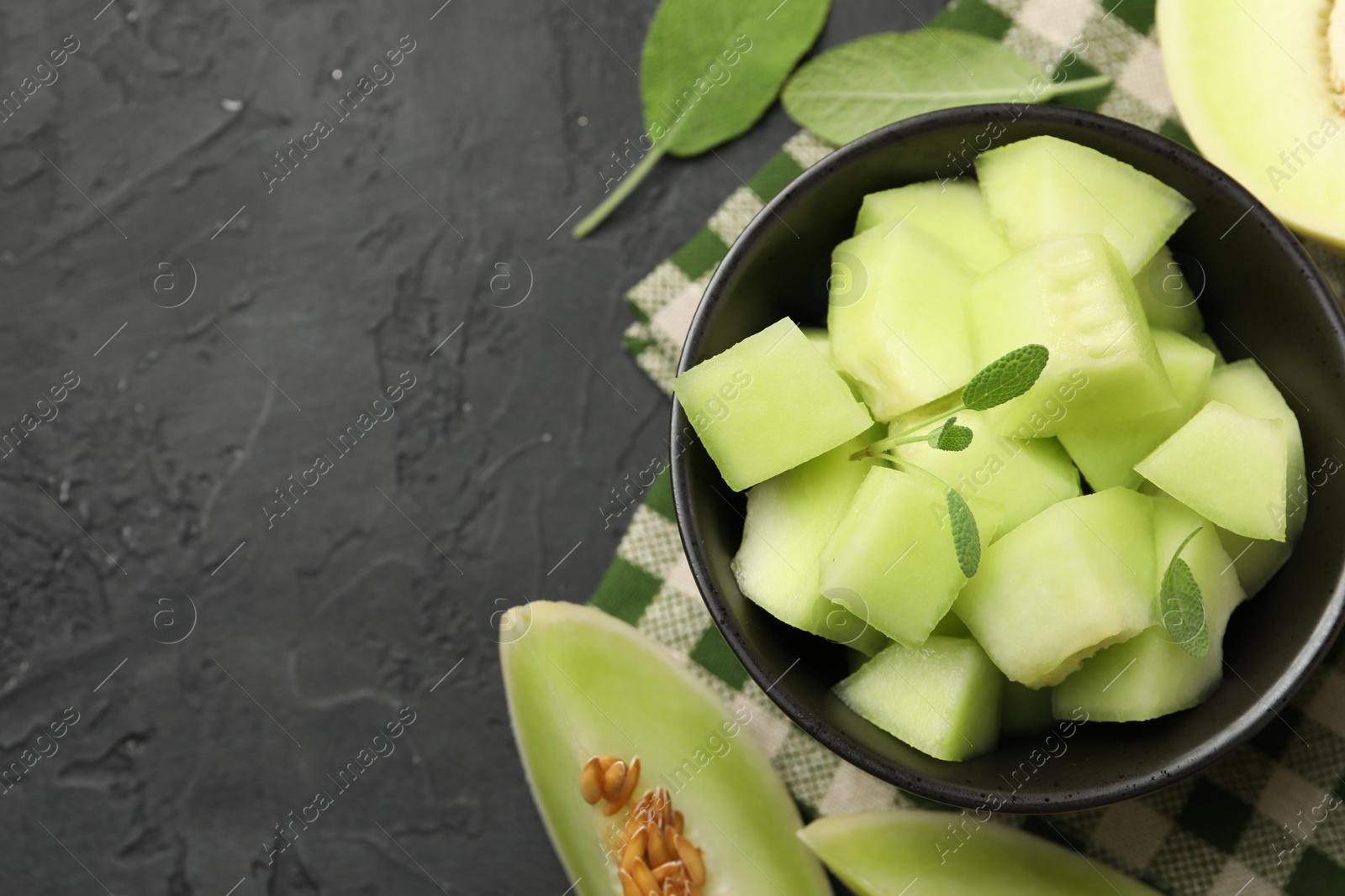 Photo of Slices of yummy melon on dark table, flat lay. Space for text