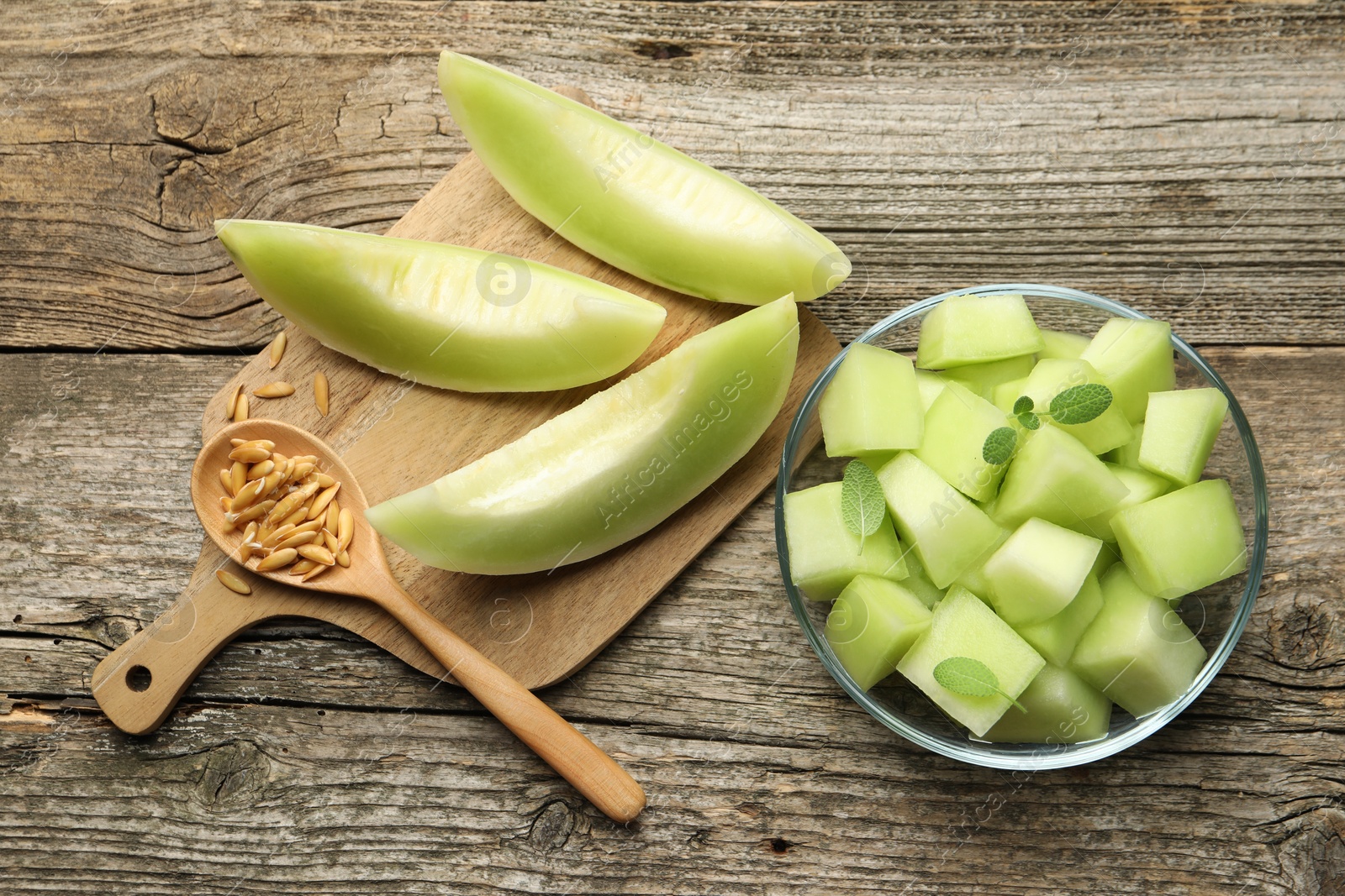 Photo of Slices of yummy melon on wooden table, flat lay