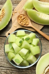 Photo of Slices of yummy melon on wooden table, flat lay