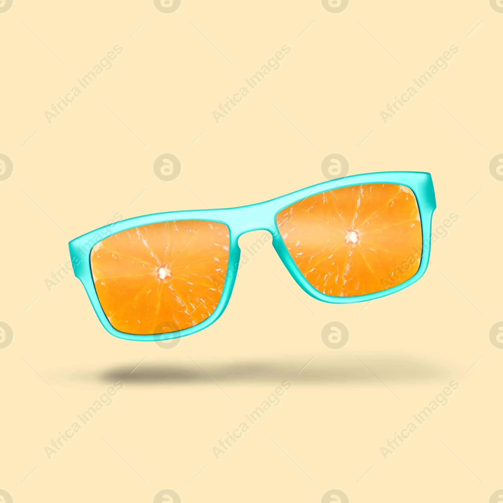 Image of Sunglasses with juicy orange in air on beige background. Summer vibe