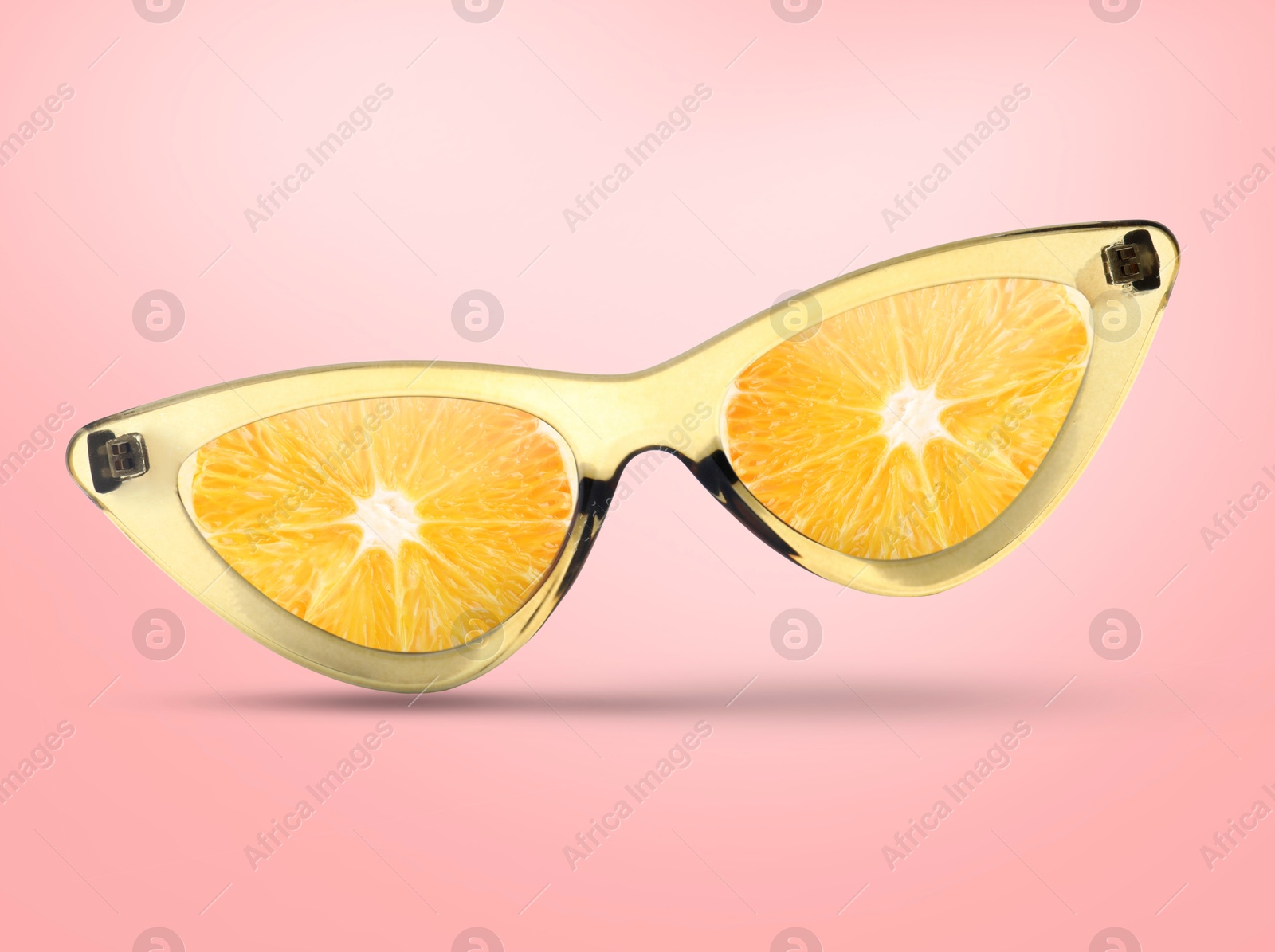 Image of Sunglasses with juicy orange in air on pink background. Summer vibe