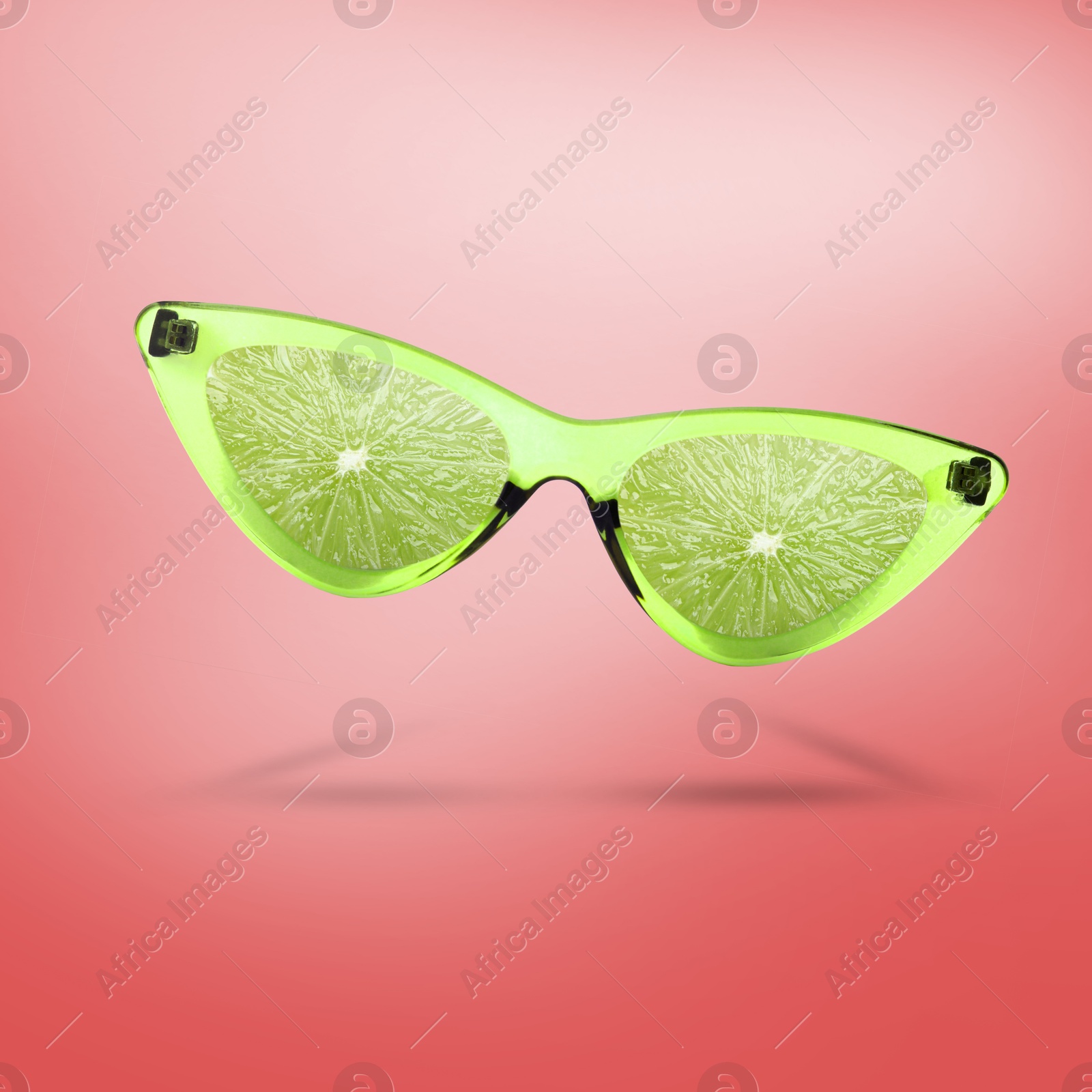 Image of Sunglasses with juicy lime in air on pink background. Summer vibe