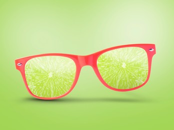 Image of Sunglasses with juicy lime in air on light green background. Summer vibe