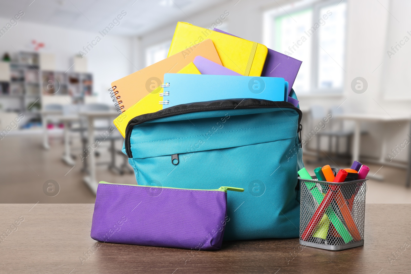 Image of Light blue backpack with stationery on school desk in classroom