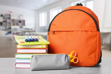 Image of Orange backpack with stationery on school desk in classroom