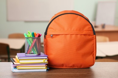 Image of Orange backpack with stationery on school desk in classroom