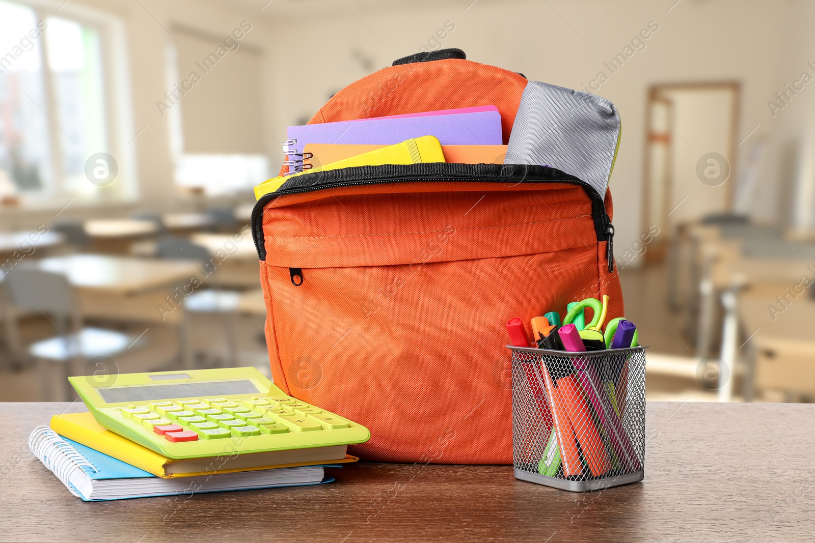 Image of Orange backpack with stationery on school desk in classroom