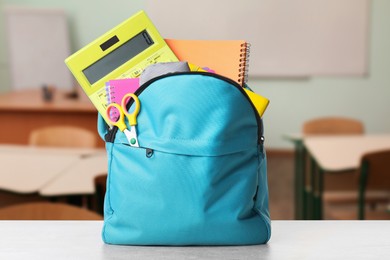 Image of Light blue backpack with stationery on school desk in classroom