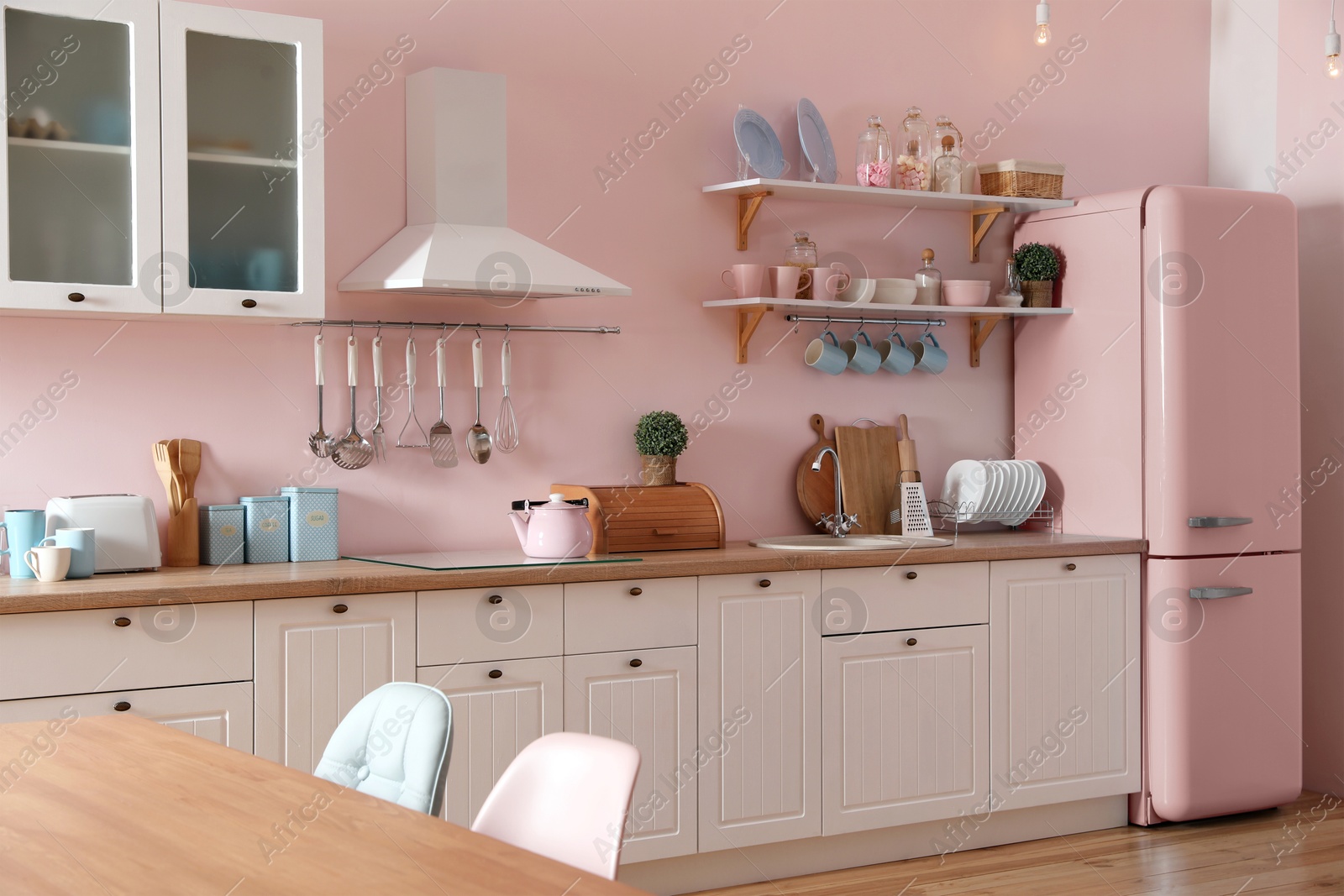 Image of Pink refrigerator in furnished kitchen. Stylish interior