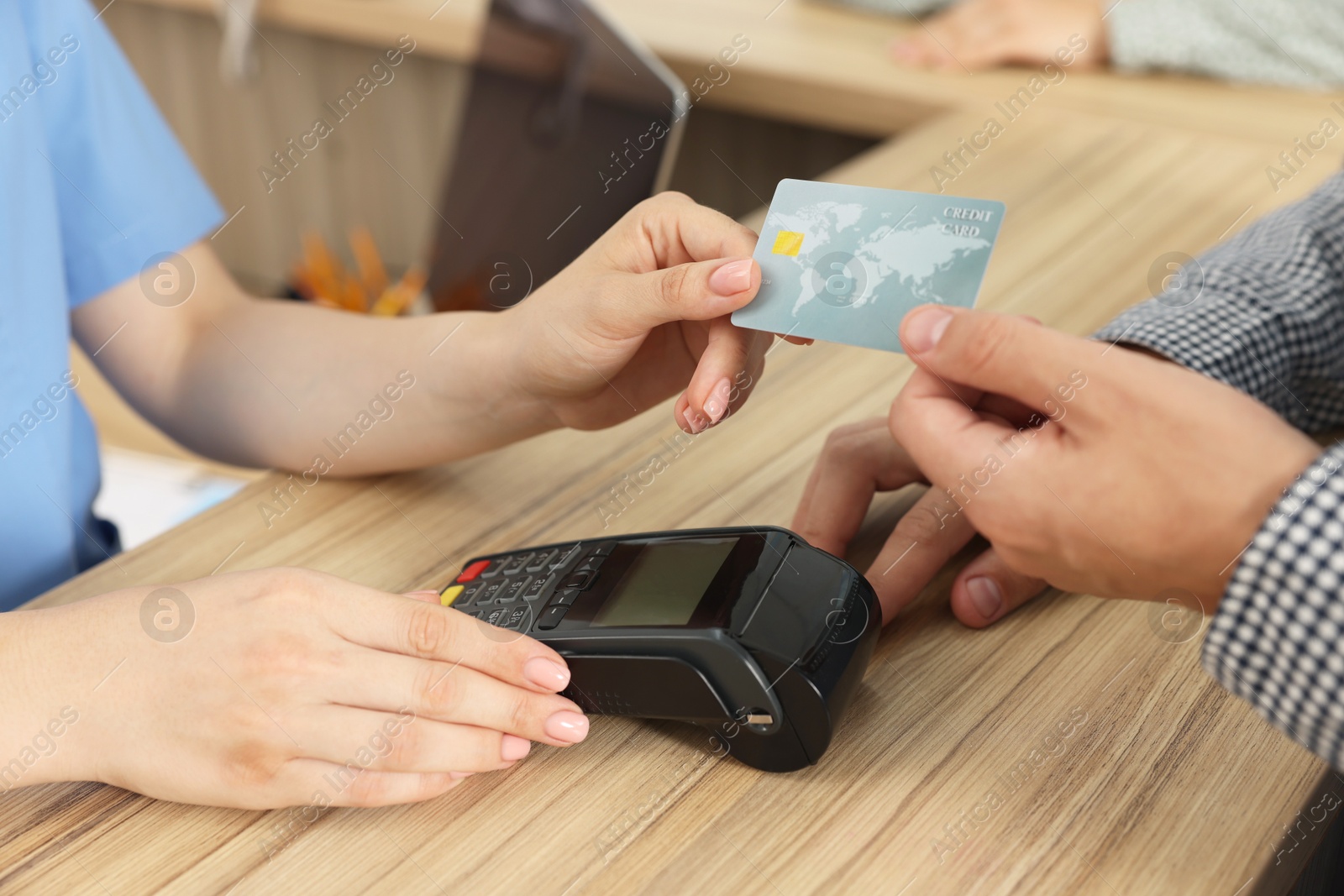 Photo of Receptionist taking payment from client via terminal at hospital, closeup