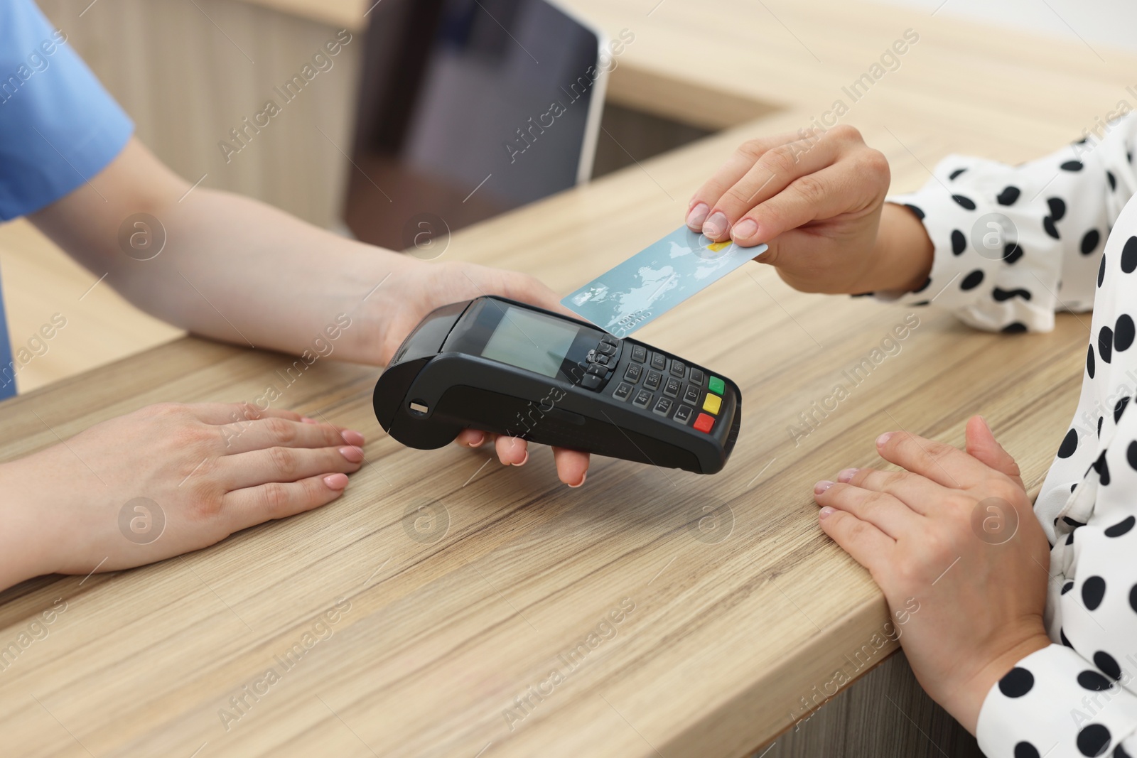 Photo of Receptionist taking payment from client via terminal at hospital, closeup