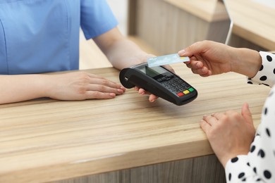 Receptionist taking payment from client via terminal at hospital, closeup