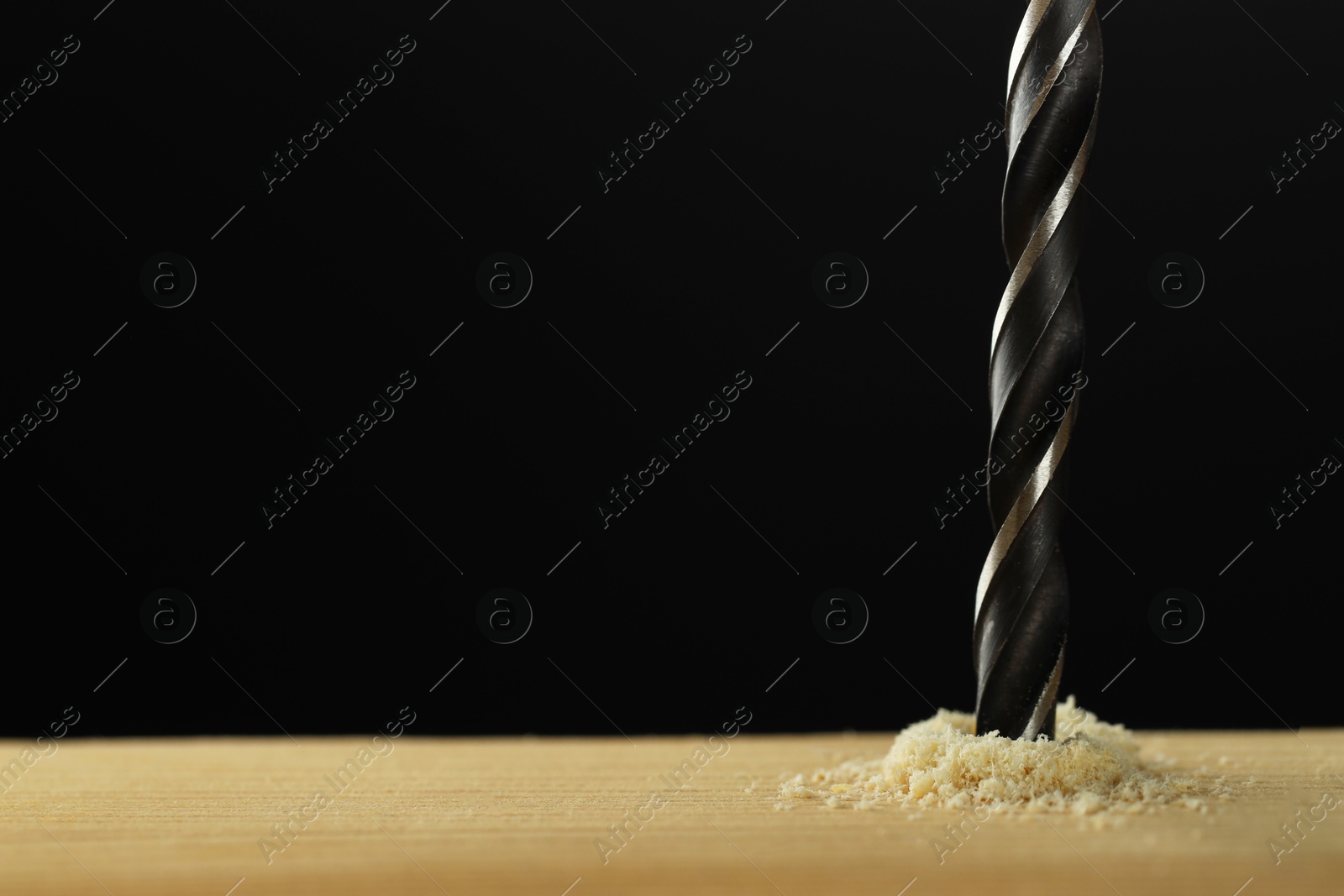 Photo of Drilling hole in wooden plank on black background, closeup. Space for text