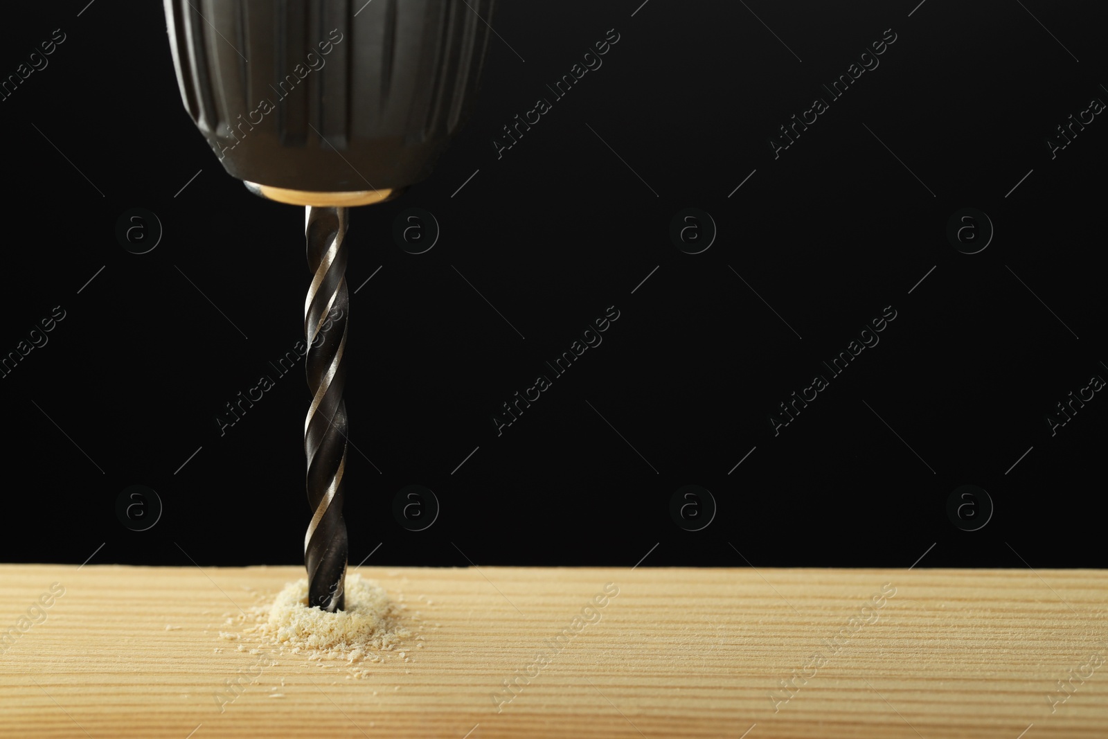 Photo of Drilling hole in wooden plank on black background, closeup. Space for text