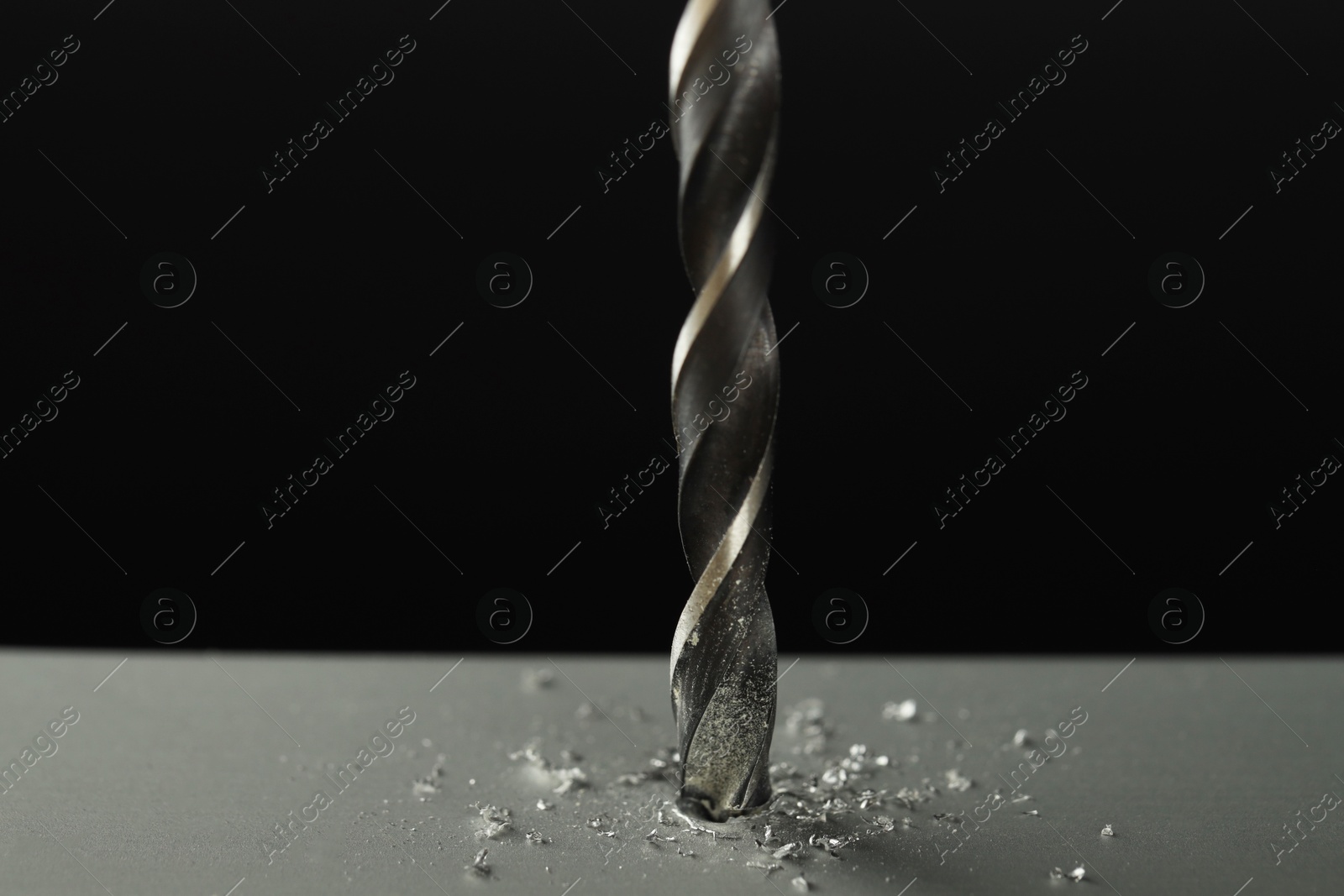 Photo of Drilling hole in grey surface on black background, closeup