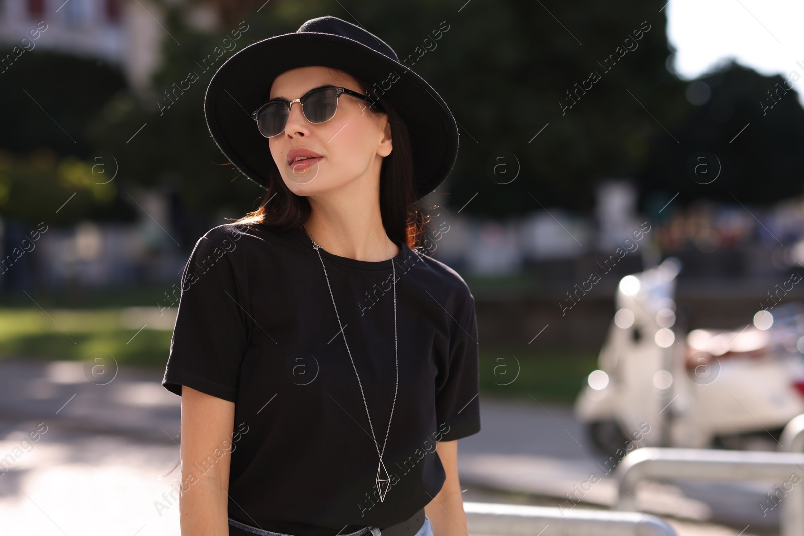 Photo of Young woman in stylish black hat and sunglasses on city street