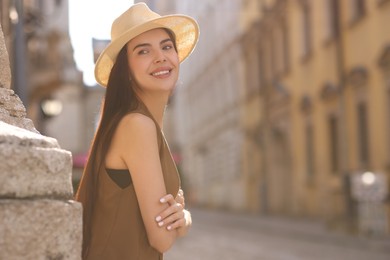 Beautiful young woman in stylish hat on city street, space for text