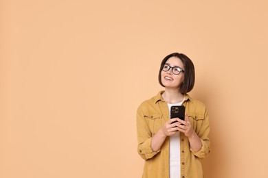 Photo of Smiling woman with smartphone on beige background. Space for text