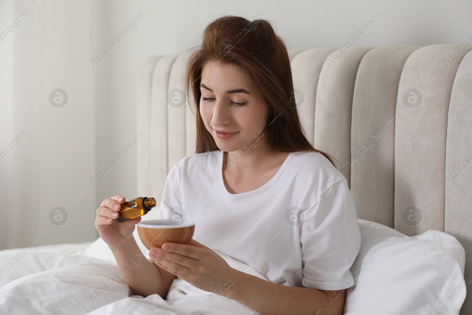 Photo of Woman adding essential oil to aroma diffuser at home