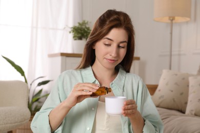 Photo of Woman adding essential oil to aroma diffuser at home