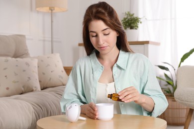 Woman adding essential oil to aroma diffuser at home