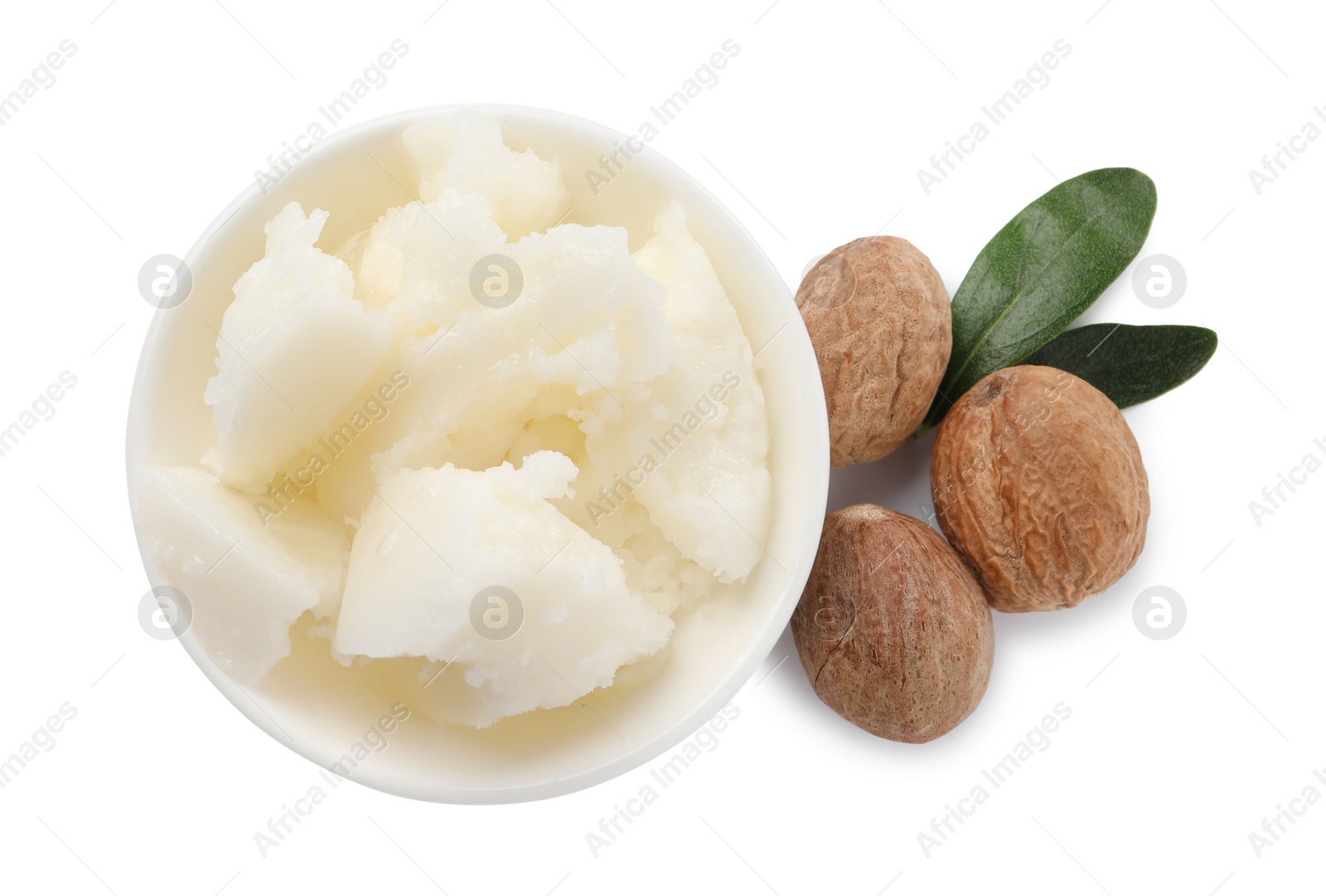 Photo of Natural shea butter in bowl, nuts and green leaves isolated on white, top view