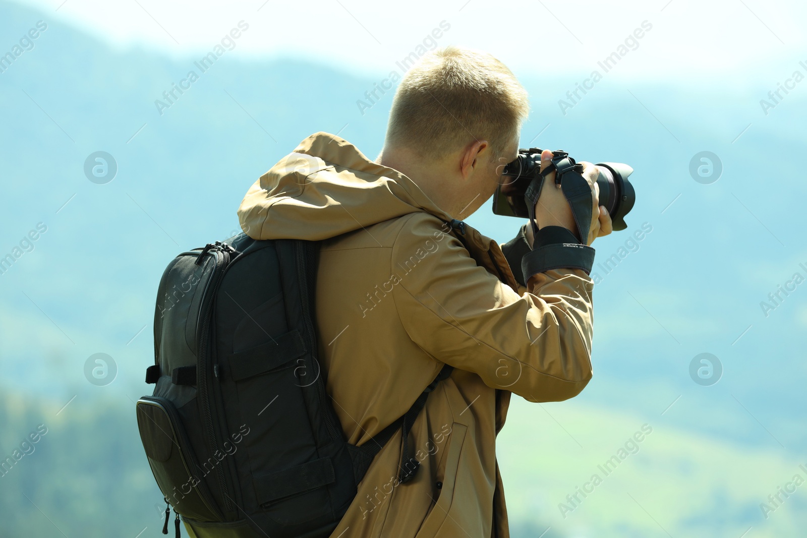 Photo of Photographer with backpack and camera taking picture of beautiful mountains