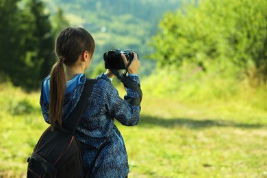 Photo of Photographer with backpack and camera taking picture outdoors, back view. Space for text