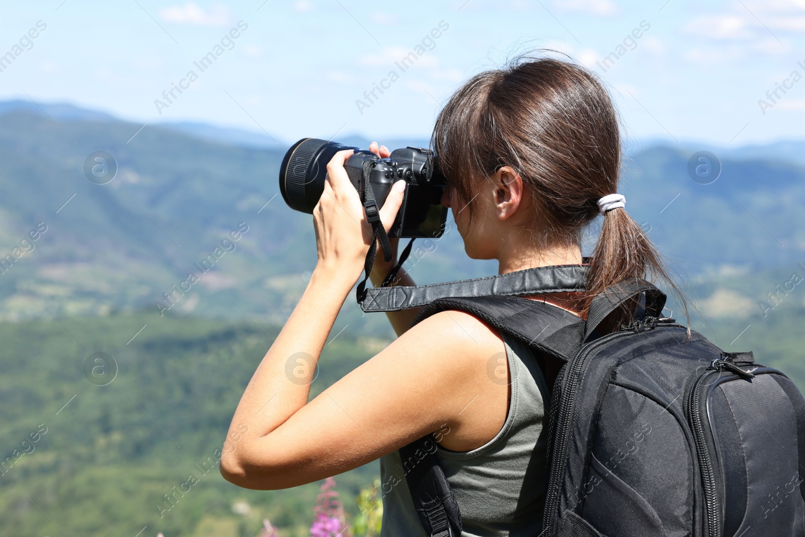 Photo of Photographer with backpack and camera taking picture of beautiful mountains